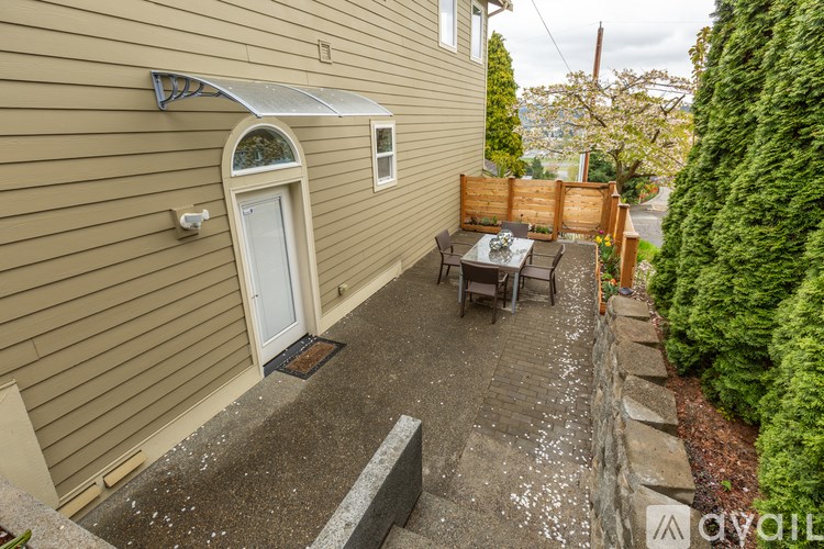 A patio with a table and chairs is surrounded by a wall and a hedge.