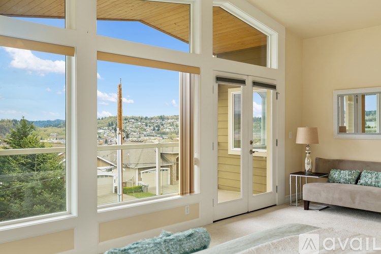A living room with a view of the town outside the large windows.
