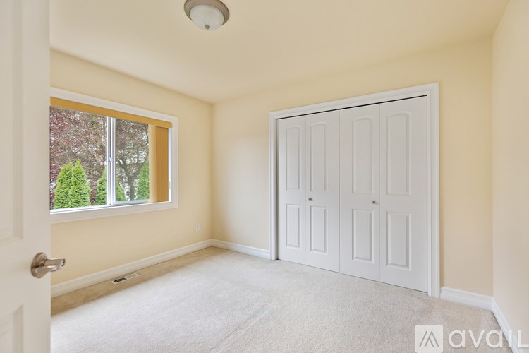A room with a white door and a window with trees visible outside.