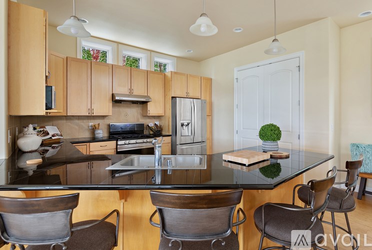 A kitchen with a black countertop and brown chairs.