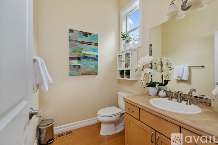 A bathroom with a toilet, sink, and a painting on the wall.