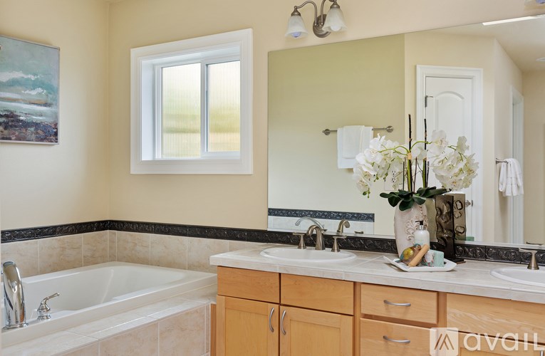 A bathroom with a tub, sink, and a painting on the wall.