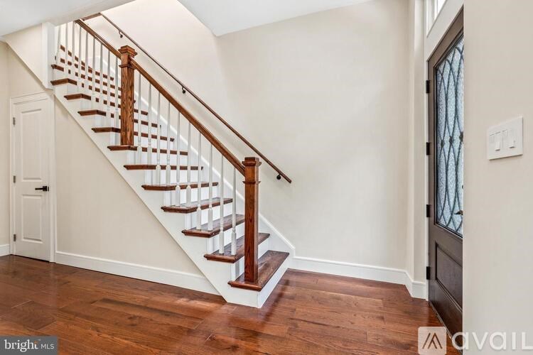 A wooden staircase with white risers and a dark brown handrail.