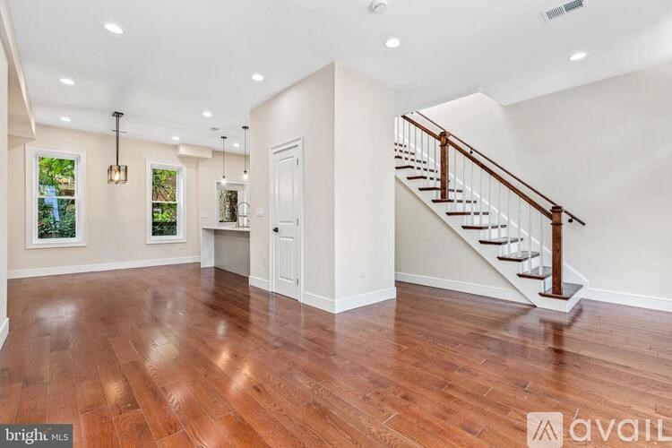 A spacious room with wooden floors and a staircase.