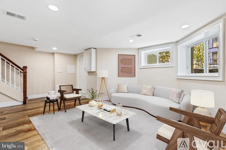 A living room with a white couch, a coffee table, and a wooden staircase.