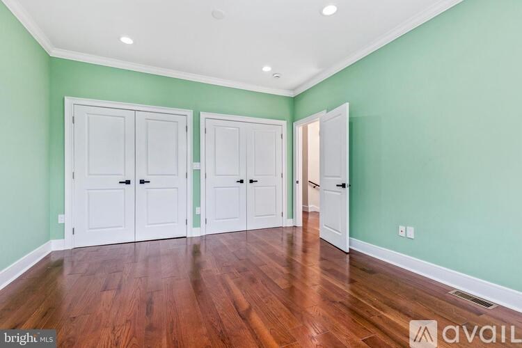 A room with green walls and wooden floors, with three doors and a window.