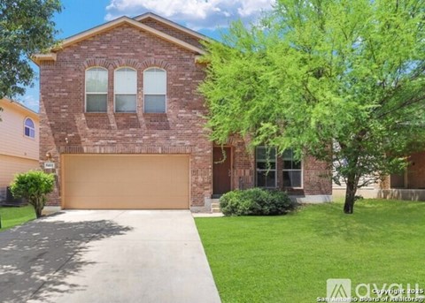 A brick house with a brown garage door and a tree in front.