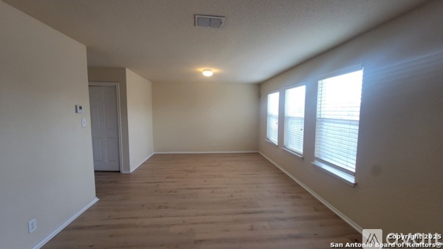 A room with wooden floors and a window with blinds.