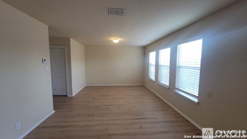 A room with wooden floors and a window with blinds.