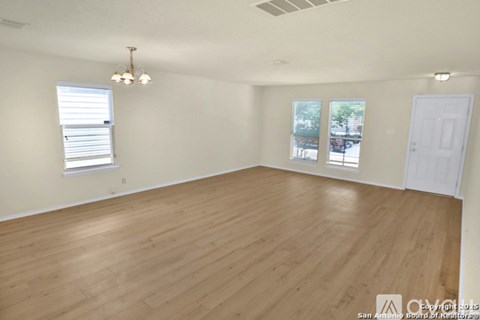 Empty room with wooden flooring and white walls.
