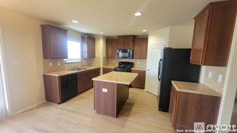 A kitchen with wooden cabinets and black appliances.