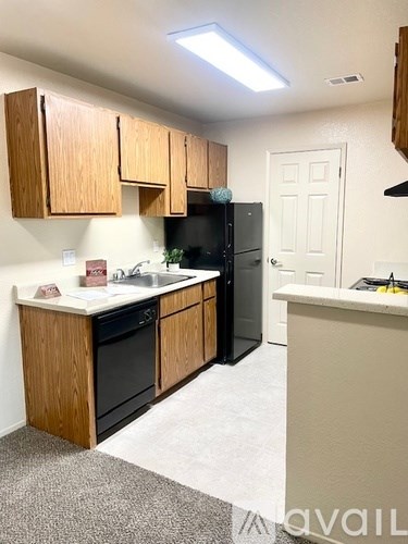 A kitchen with wooden cabinets and a black refrigerator.
