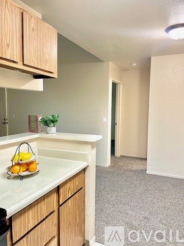 A kitchen with wooden cabinets and a bowl of fruit on the counter.