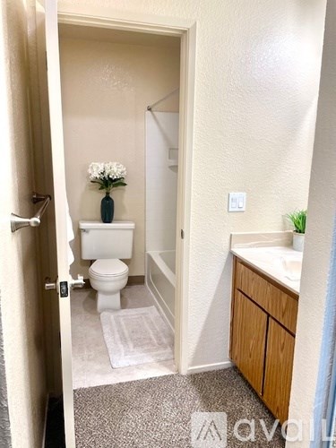A small bathroom with a toilet, sink, and a vase of flowers.