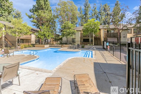 A pool surrounded by trees and chairs.