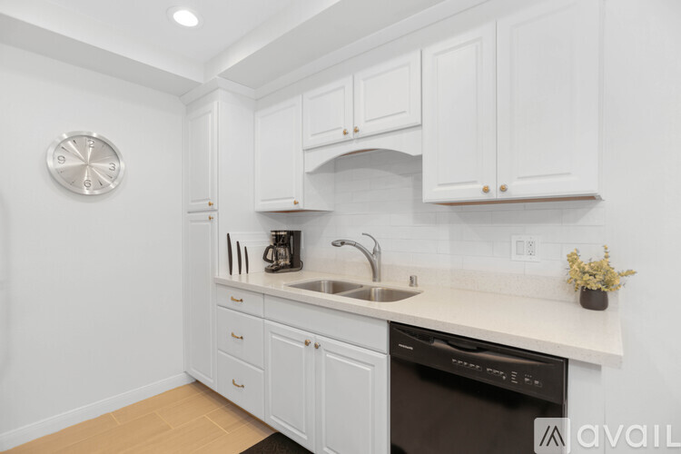 A kitchen with white cabinets and a black dishwasher.