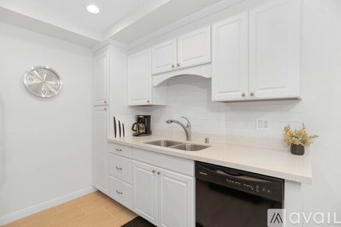 A kitchen with white cabinets and a black dishwasher.