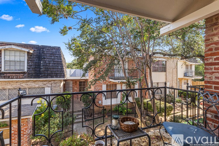 A patio with a table and chairs overlooks a tree and a house.