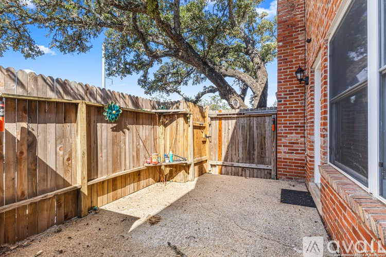 A backyard with a wooden fence and a tree.