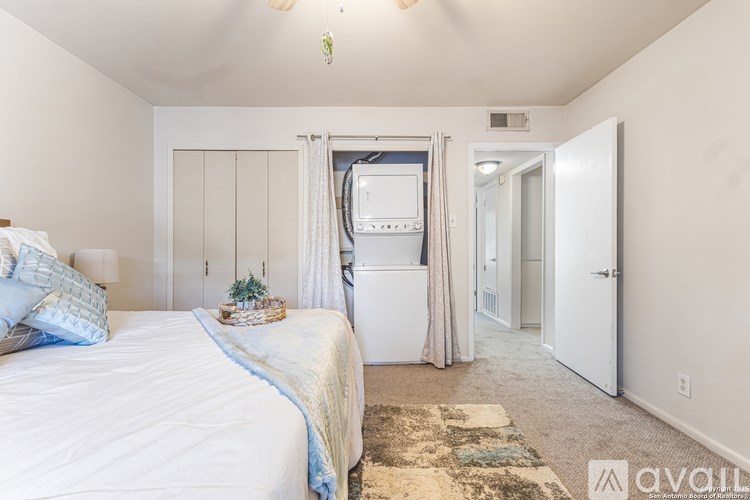 A bedroom with a bed, a washing machine, and a window.