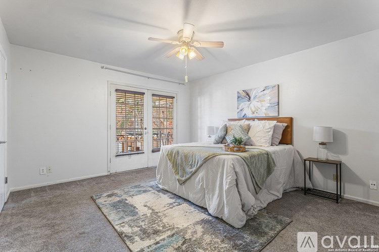 A bedroom with a bed, a rug, and a ceiling fan.