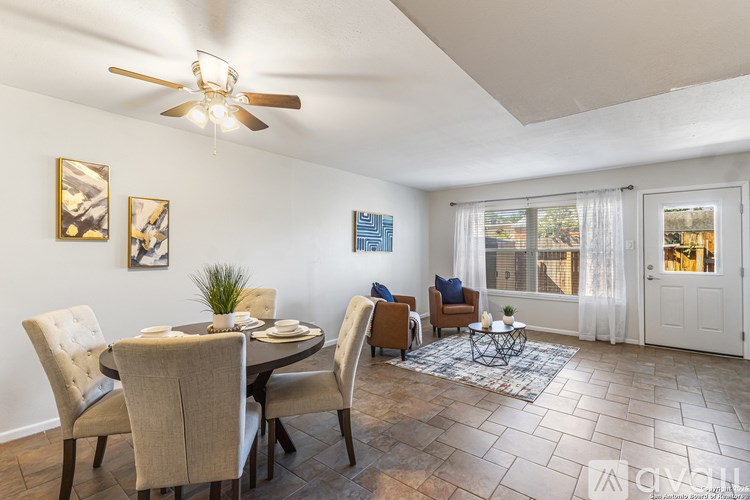 A dining room with a table set for two and a couch with a view of the backyard.