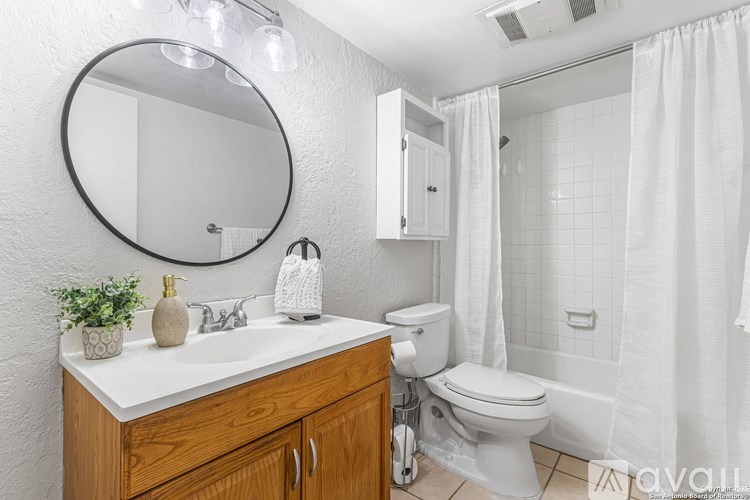 A bathroom with a white sink, toilet, and shower area.