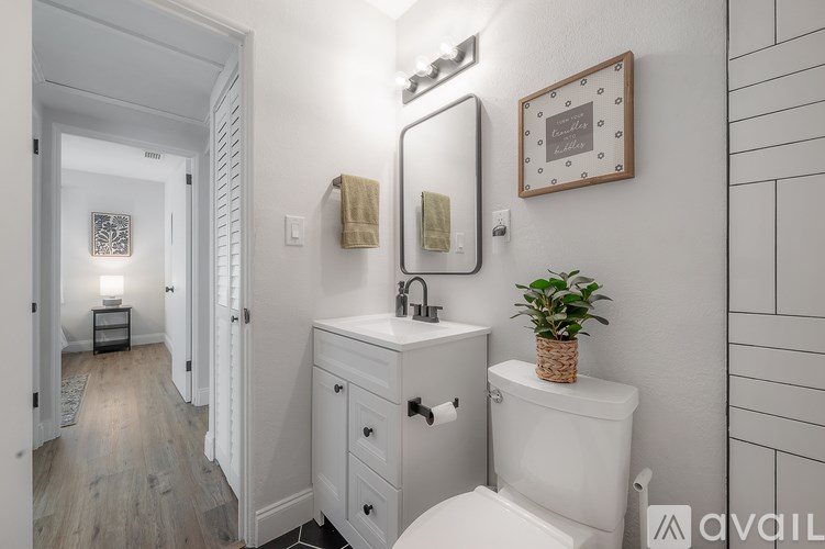 A bathroom with a toilet, sink, and mirror.