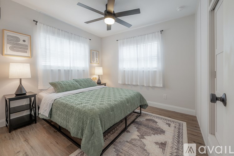 A bedroom with a bed, two lamps, and a ceiling fan.
