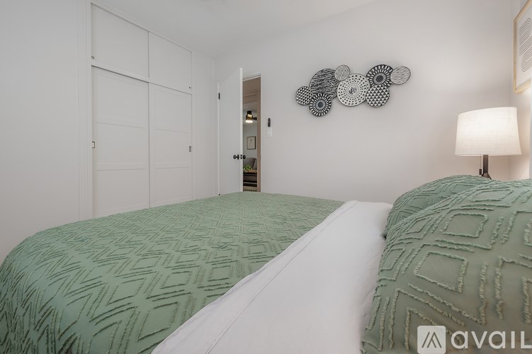 Two beds with green bedspreads in a white room.