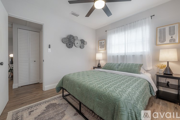 A bedroom with a bed, two lamps, and a ceiling fan.