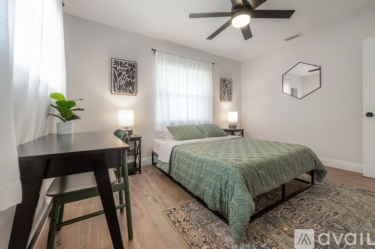 A bedroom with a bed, a table, and a ceiling fan.