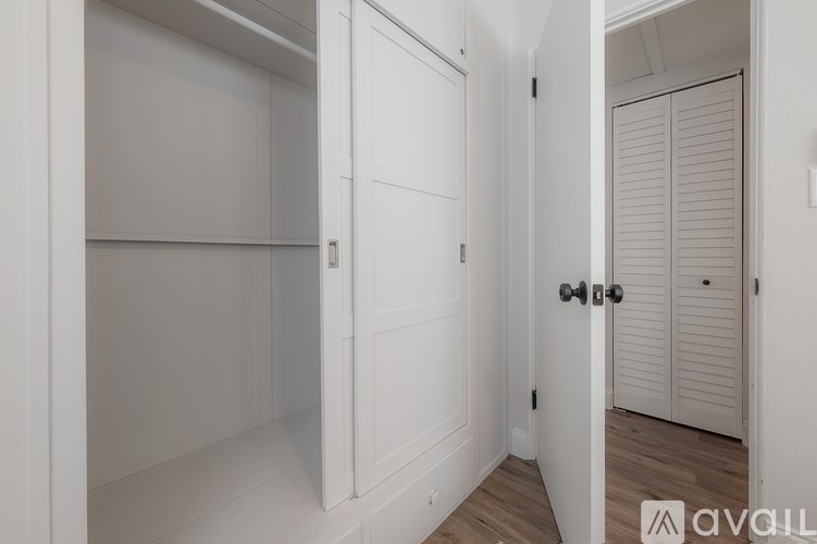 A white door with a black handle is open to a hallway.