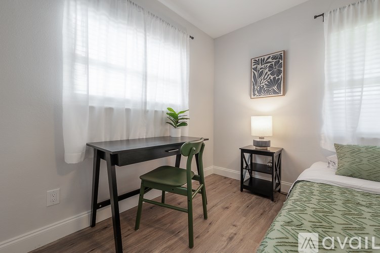 A room with a bed, desk, chair, and lamp.