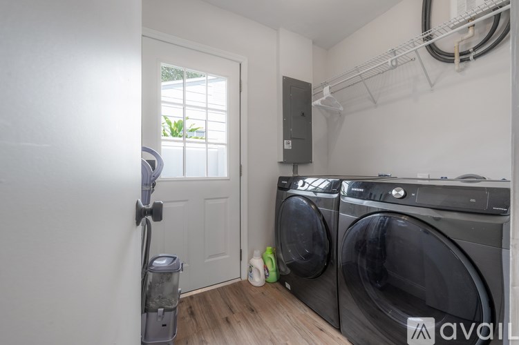 A laundry room with a washer and dryer, a door, and a window.