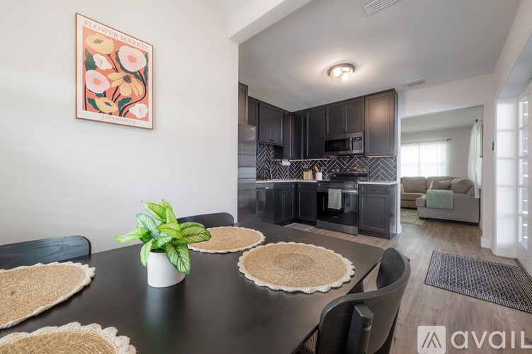 A modern kitchen with a black table and a framed picture on the wall.