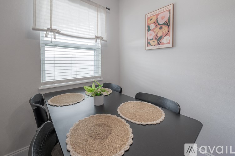 A dining table with a plant and a picture on the wall.