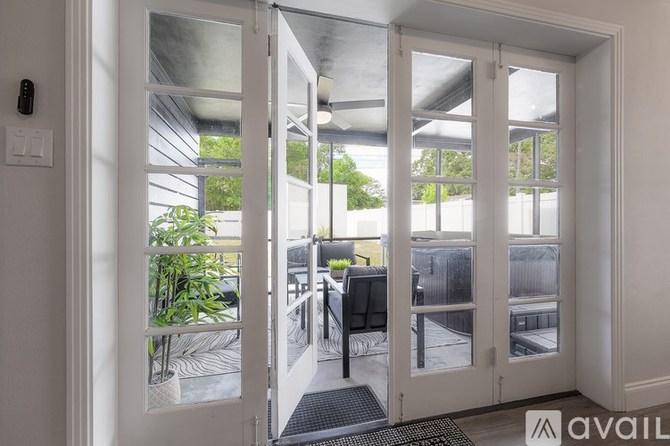 A white door with glass panels is open, revealing a patio with a table and chairs.