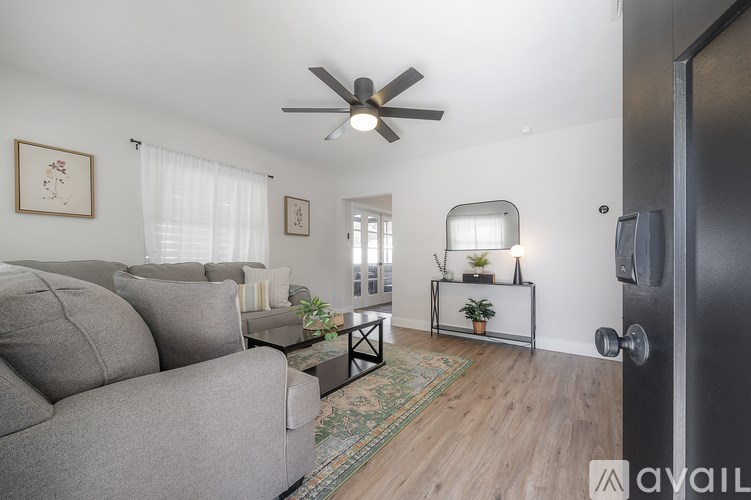 A living room with a grey couch and a ceiling fan.