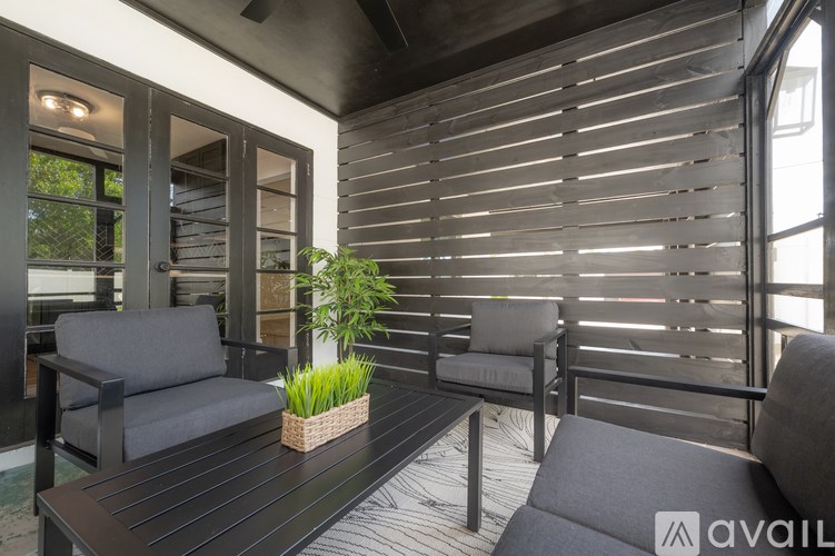 A patio with a table, chairs and a plant.