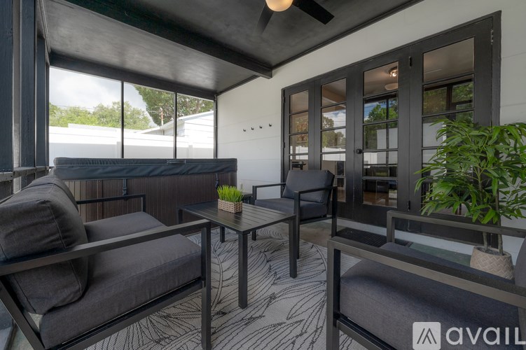 A modern outdoor seating area with a glass table and grey couches.