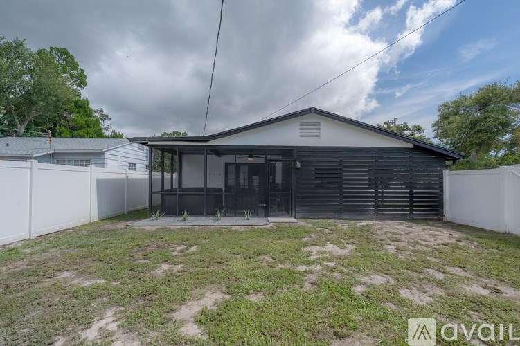 A house with a black roof and a white fence is available for sale.