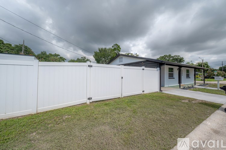 A house with a grey roof and a white fence is available for sale.