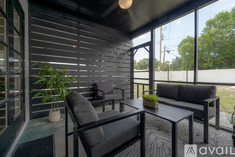 A patio with a black couch and a table with a plant on it.