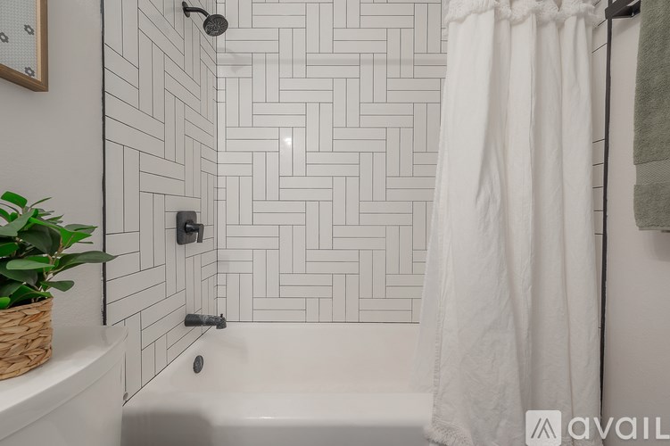A bathroom with a white shower curtain and a basket of green plants.