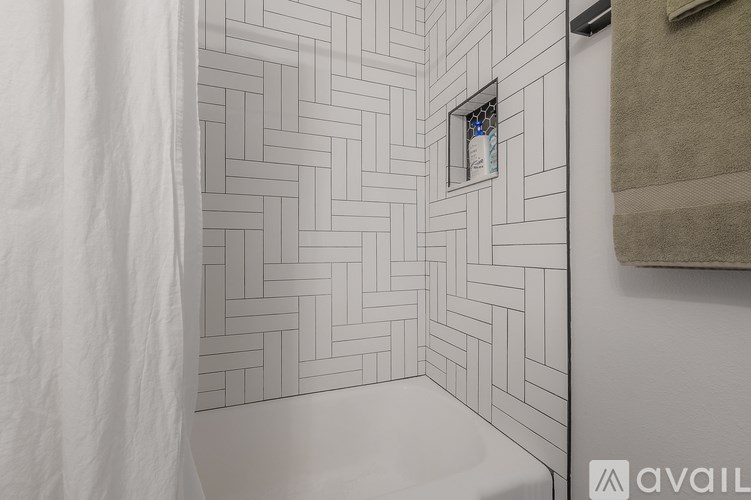 A bathroom with a white tiled wall and a small picture frame on it.