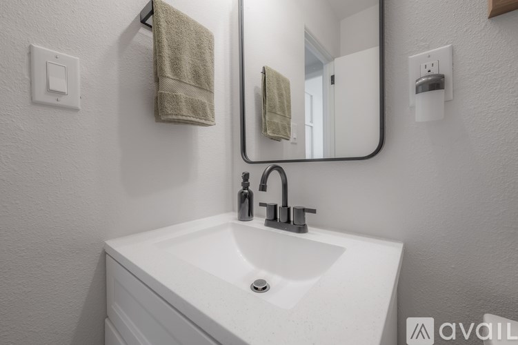 A white sink with a silver faucet and a towel hanging on the wall.