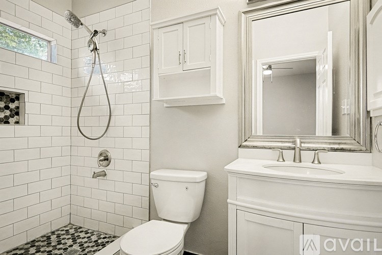 A white bathroom with a toilet, sink, and shower.