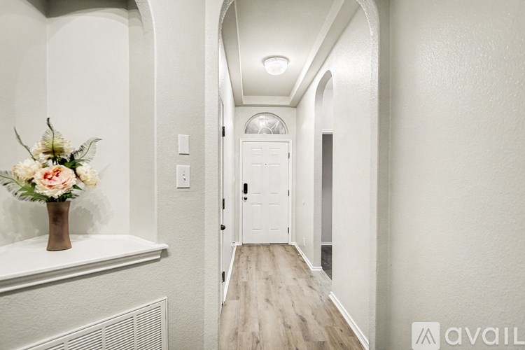 A hallway with a vase of flowers on a ledge.