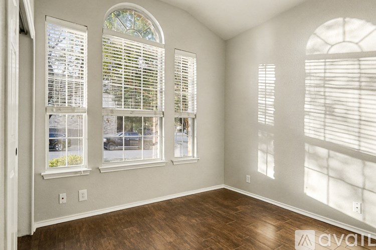 A room with wooden floors and three windows with blinds.